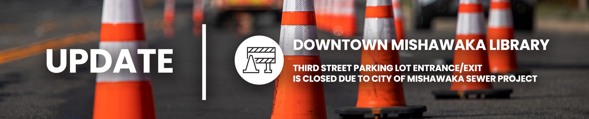 Reflective traffic cones on the street and image text, ‘DOWNTOWN MISHAWAKA LIBRARY THIRD STREET PARKING LOT ENTRANCE/EXIT IS CLOSED DUE TO CITY OF MISHAWAKA SEWER PROJECT’