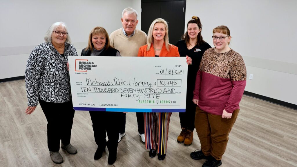 Six people stand as two of them hold a giant rebate check from I&M Power in the amount of $10,745.