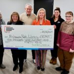 Six people stand as two of them hold a giant rebate check from I&M Power in the amount of $10,745.