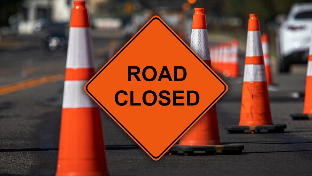 Reflective traffic cones on the street and image text, ’ROAD CLOSED’