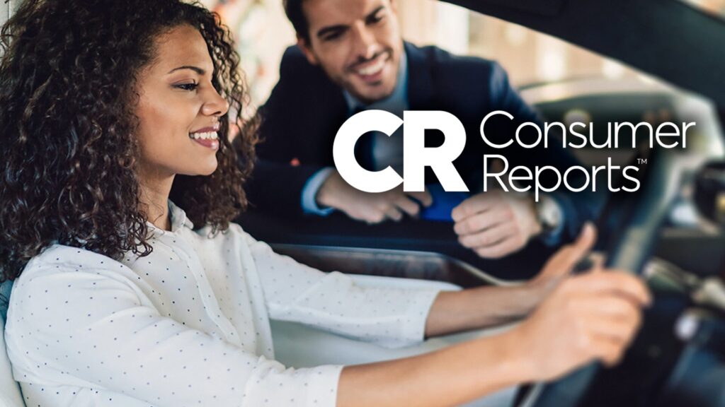 A woman behind the wheel of a car and a male salesperson leaning in the window. Consumer Reports logo