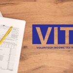 Goodwill logo. A 2024 1040 tax form, pencil and calculator. ‘VITA Volunteer Income Tax Assistance’