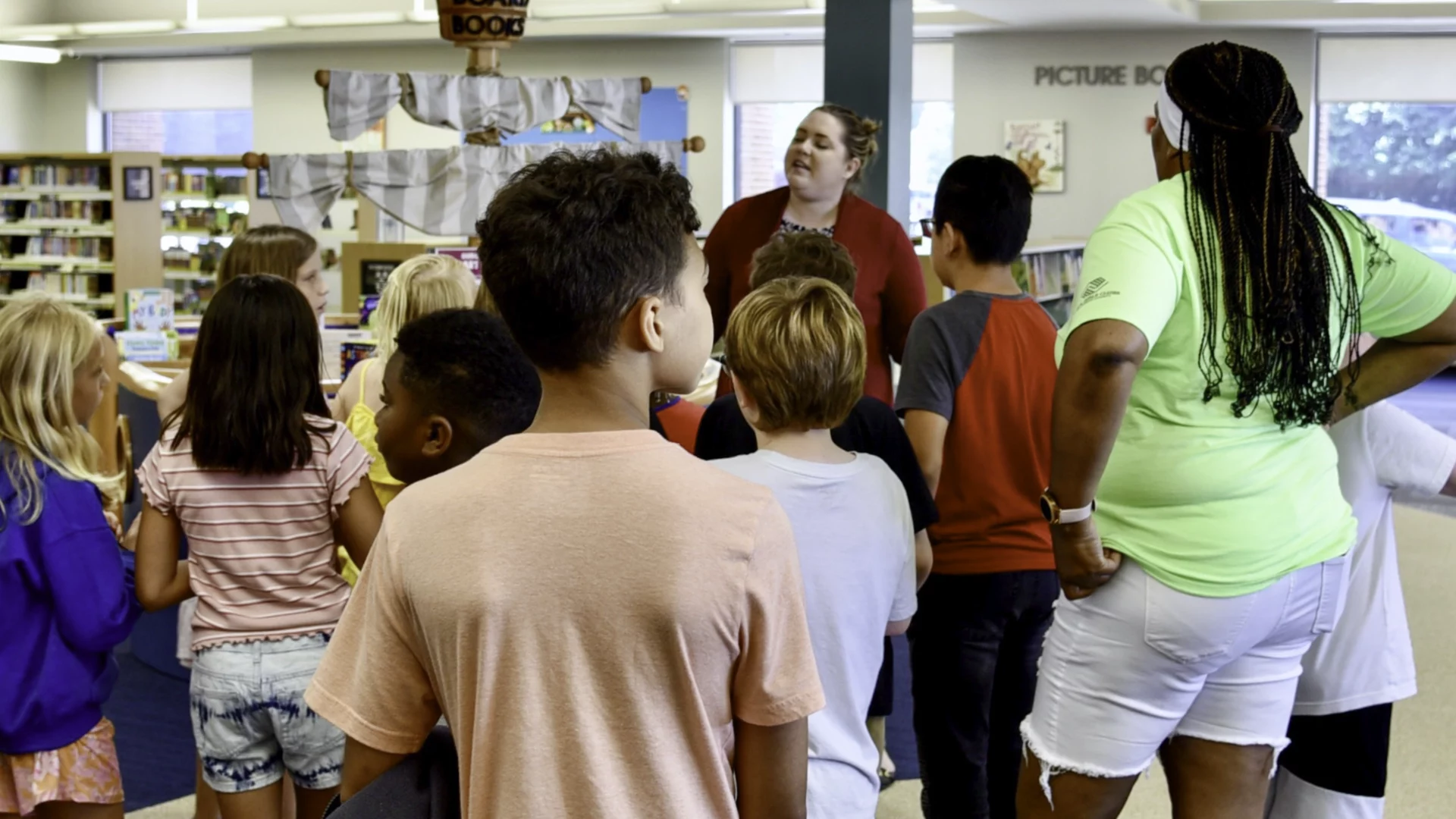 Photo_Class-Visits_Book-A-Tour A employee leads a group of children through the Youth Area at the Mishawaka Library.