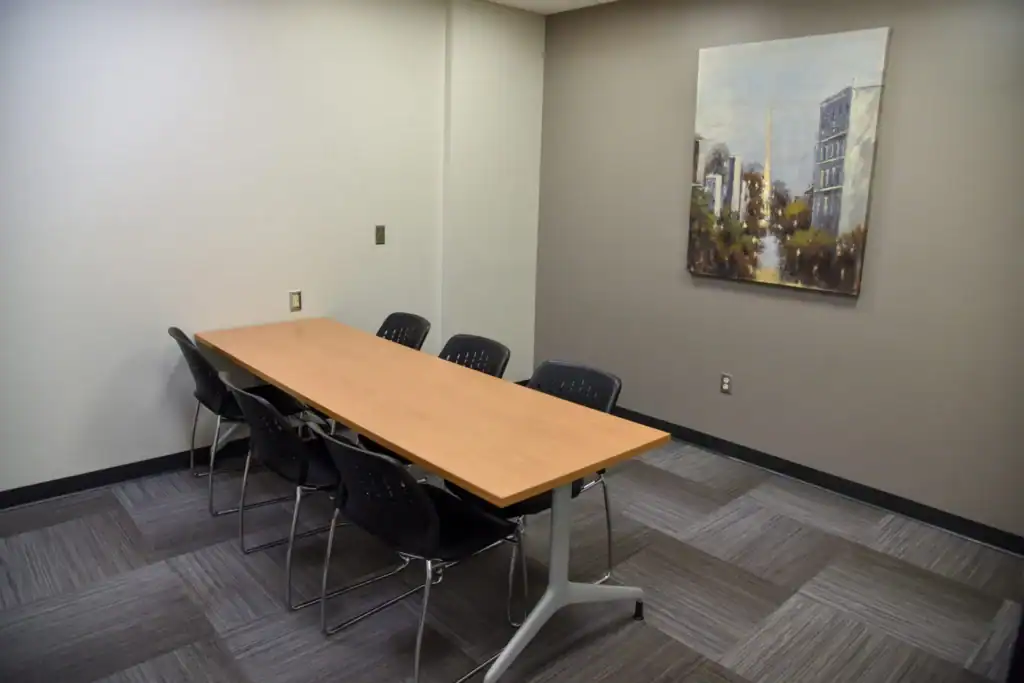 The Mishawaka Library Adult Study Room Two containing a long table against the back wall with six chairs. Right wall features a painting of a city.