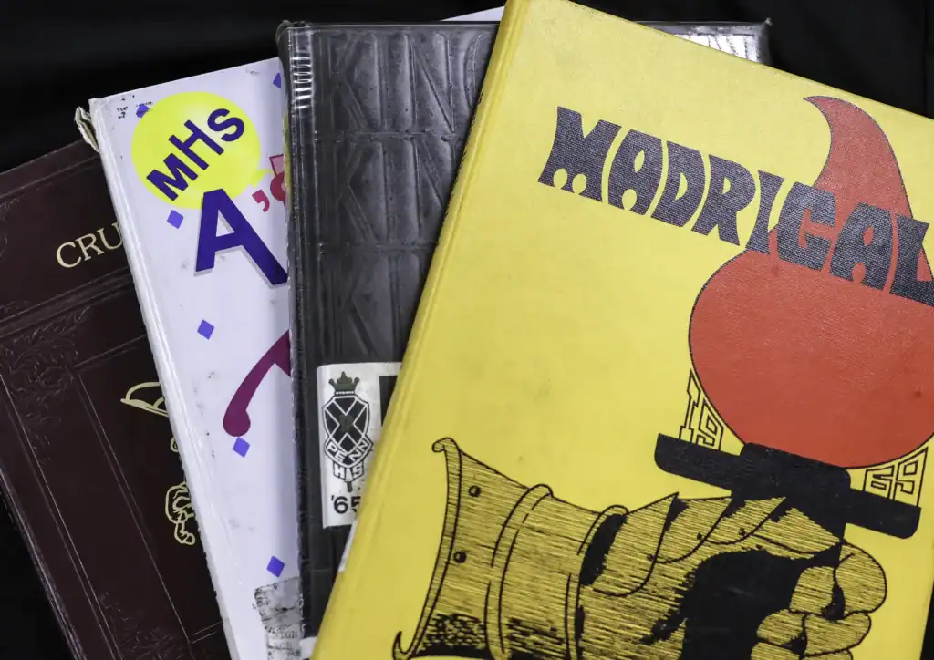 A stack of yearbooks and their high schools Madrigal Marian, Bittersweet Penn, Miscodeed Mishawaka and Madisonian from former Madison Township.