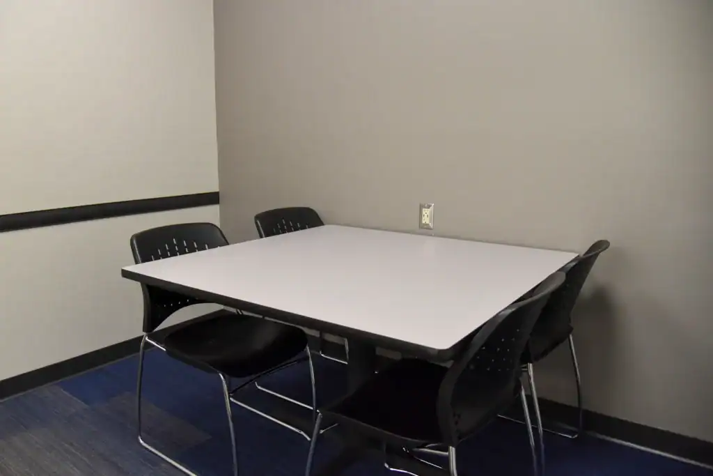 The Mishawaka Library Youth Study Room Two containing a table with four chairs. The back wall has a power outlet.
