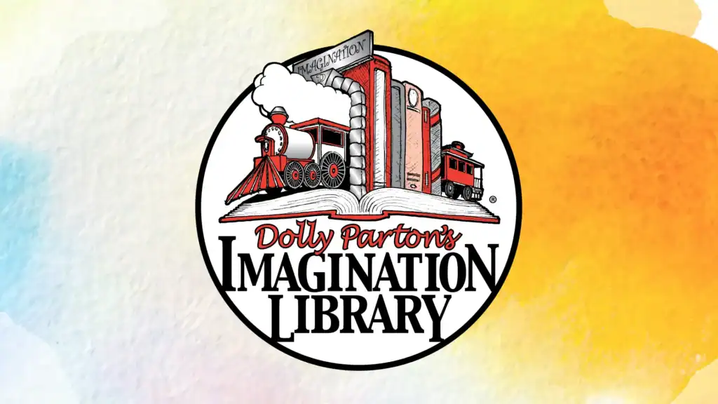 Logo for Dolly Partons Imagination Library featuring a red train emerging from an open book, with text Dolly Partons Imagination Library on a circular white background with a pastel watercolor border.